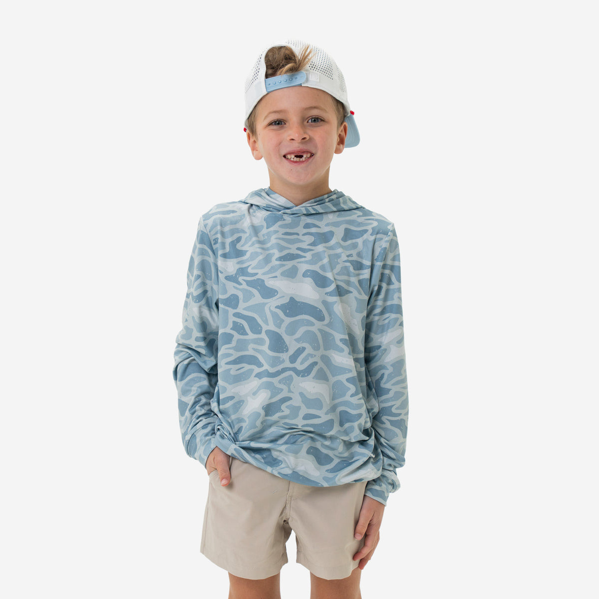 Child wearing a blue camouflage performance hoodie and beige shorts on a white background.