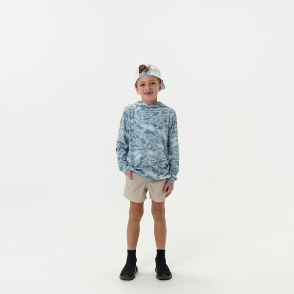 Child wearing a blue camouflage hoodie and beige shorts on a white background