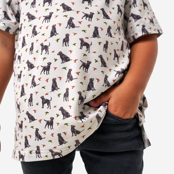 Child wearing a shirt with a dog and duck pattern on a white background