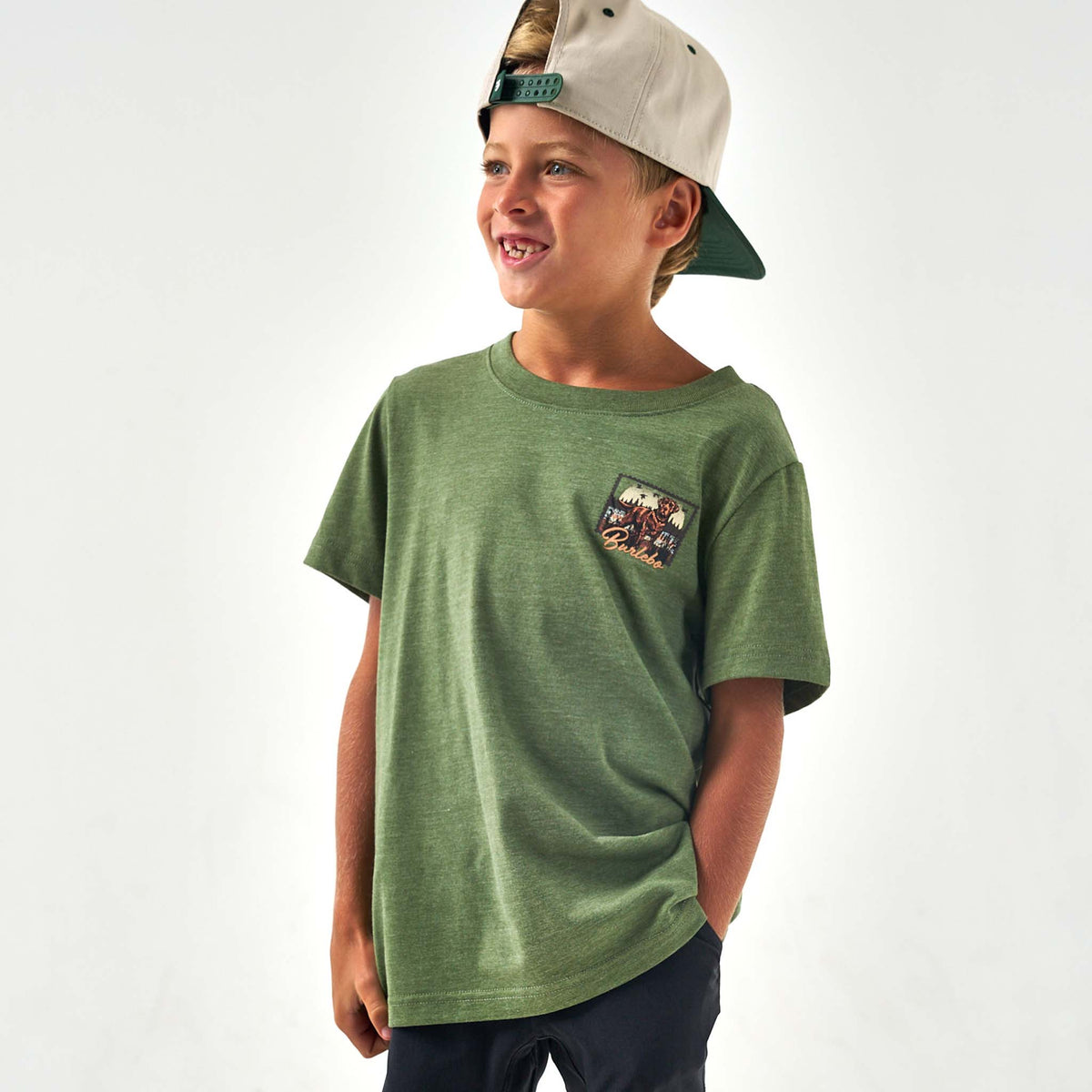 Child wearing a green t-shirt with a small graphic on a white background