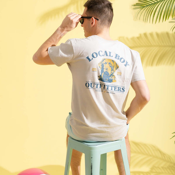 Person wearing a 'Local Boy Outfitters' t-shirt against a yellow background