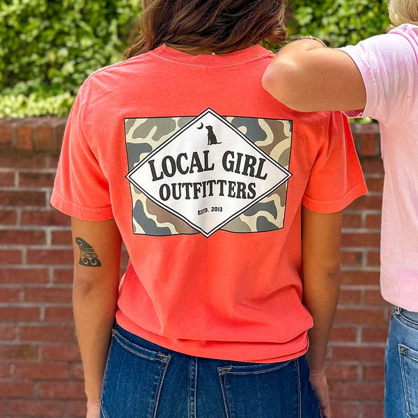 Local Girl Outfitters short sleeve t-shirt, bright salmon, sizes S-XXL, 100% cotton. Woman wearing the shirt in an outdoor setting showing the back design.